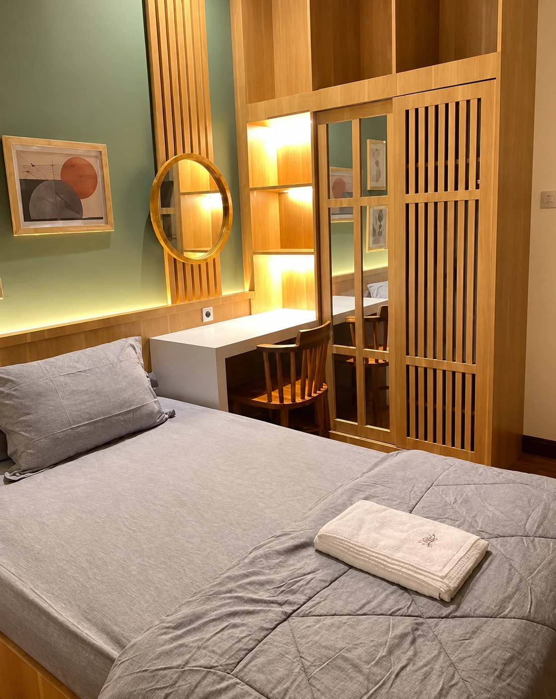 Kamar Omahe Janeet dengan tempat tidur, meja, cermin bulat, dan lemari kayu